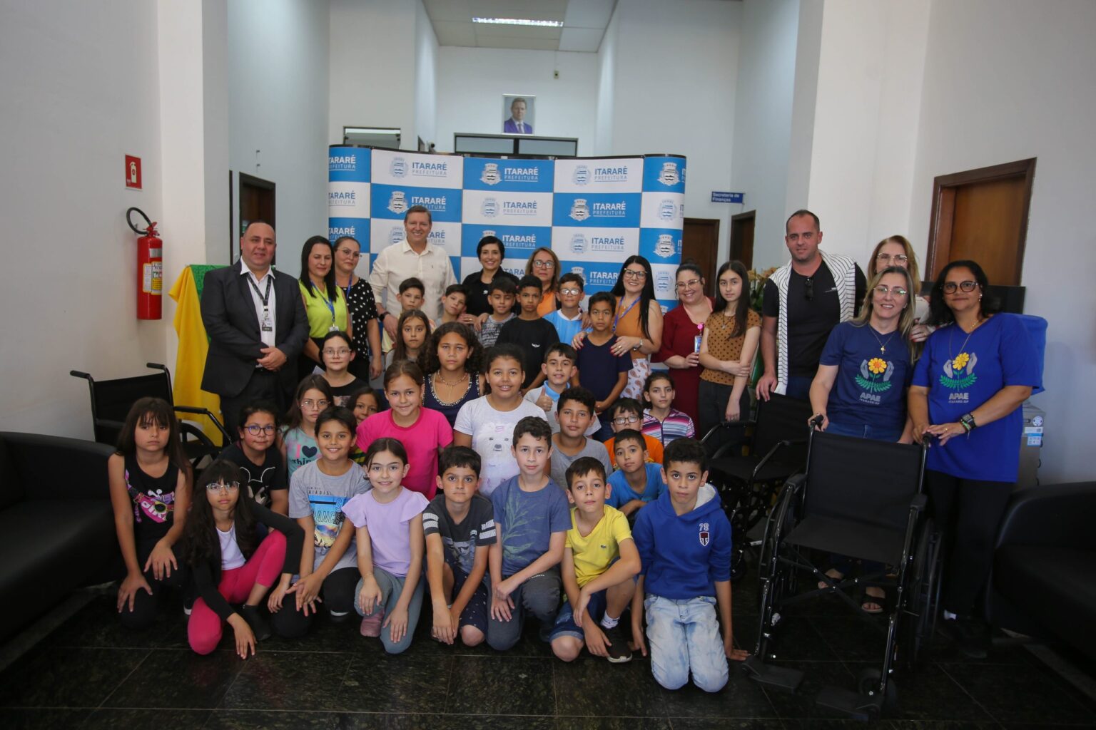 Ao lado de estudantes, prefeito de Itararé (SP), Heliton do Valle, entrega cadeiras de rodas à entidades