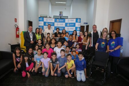Ao lado de estudantes, prefeito de Itararé (SP), Heliton do Valle, entrega cadeiras de rodas à entidades